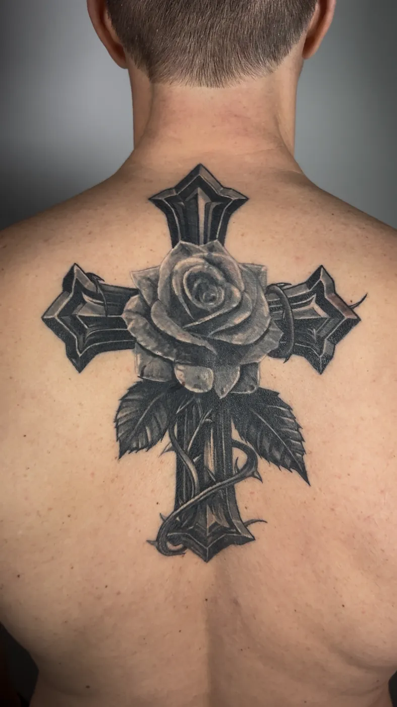Croix gothique et rose réaliste, tatouée en haut du dos, noir et gris.